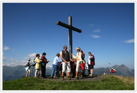 Menschen auf Berg vor Gipfelkreuz