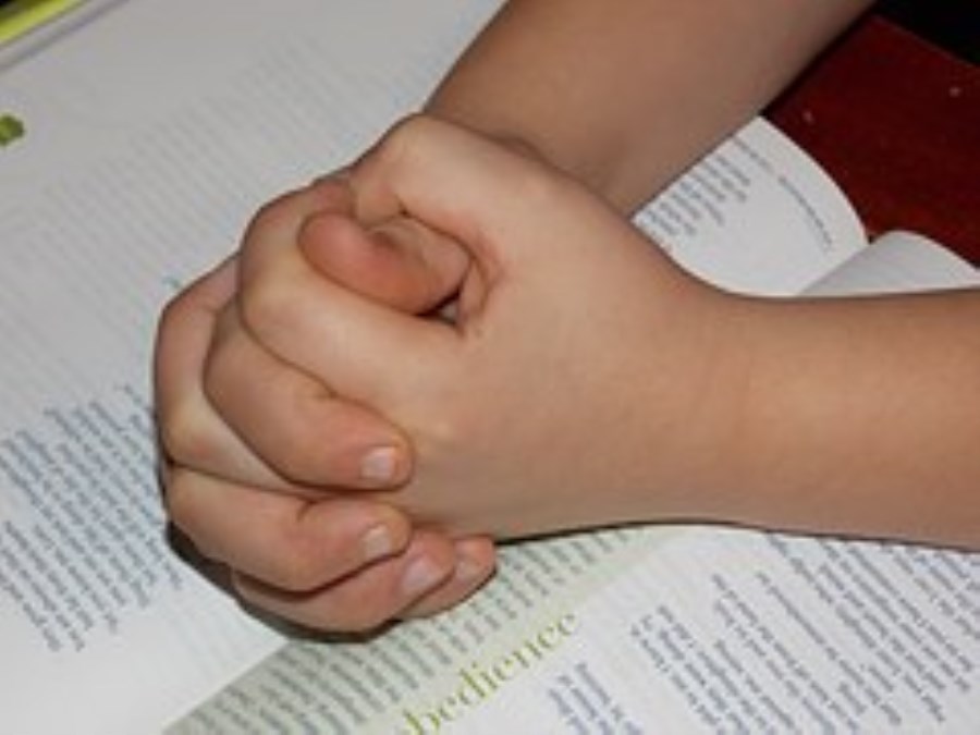 Kinderhände gefaltet auf Bibel