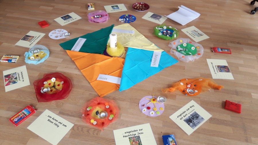 runde Tücher mit Legematerial, in der Mitte Kreuz und Bildkarten zum christlichen Menschenbild