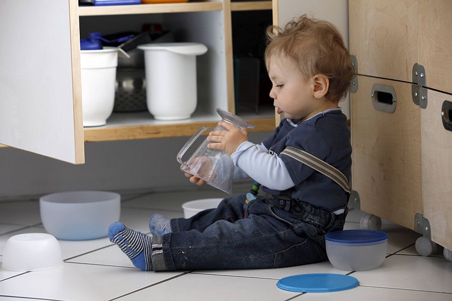 Kind räumt Küchenschrank aus
