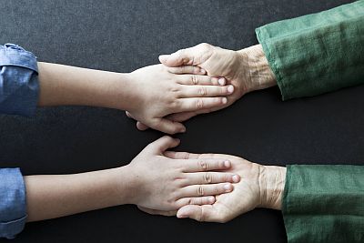 zwei Kinderhände liegen in zwei Großelternhänden