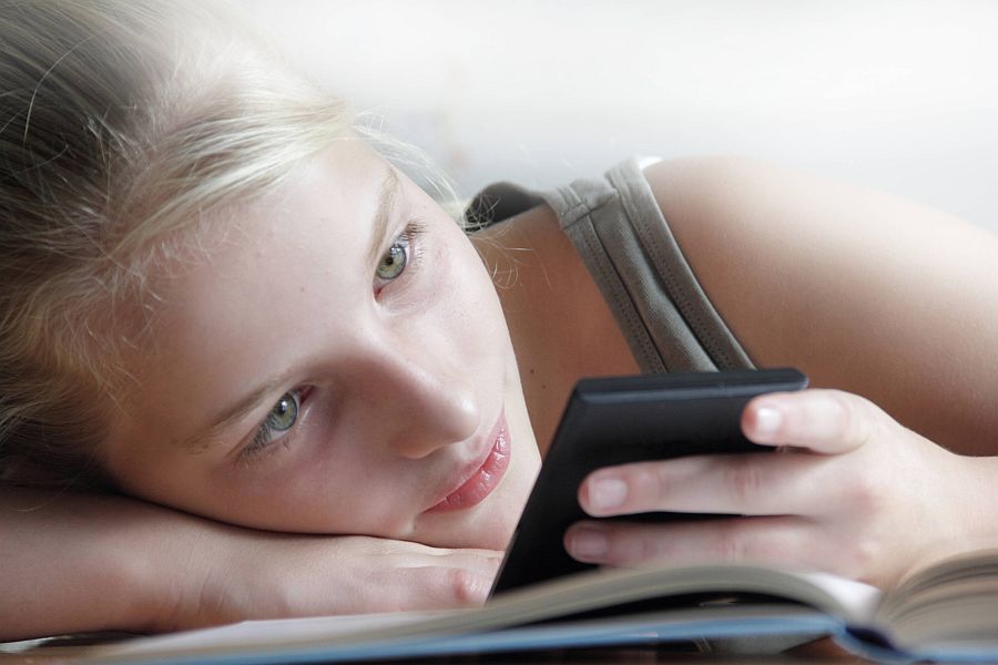 Jugendliche schaut fasziniert auf Smartphone