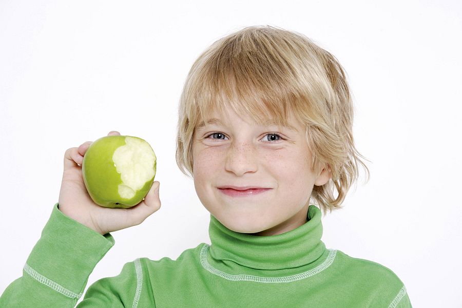 Junge zeigt fröhlich einen angebissenen Apfel
