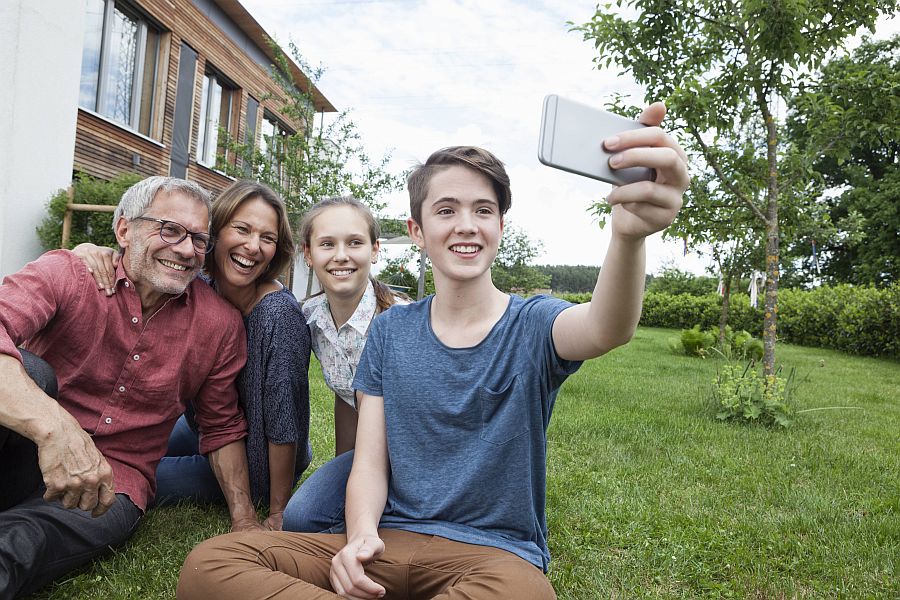 Familie mit Teenagern macht Selfie im Garten.