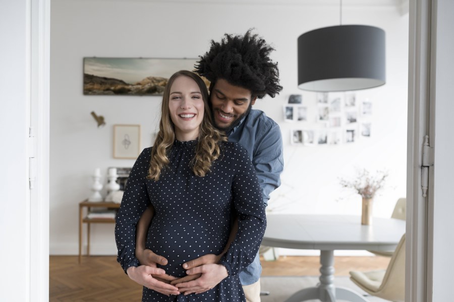 junges Paar sie schwanger er dunkelhäutig umarmt zusammen Babybauch