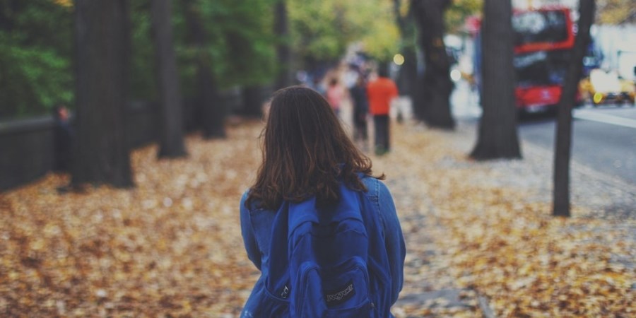 Mädchen mit Rucksack auf herbstlichem Weg in Großstadt