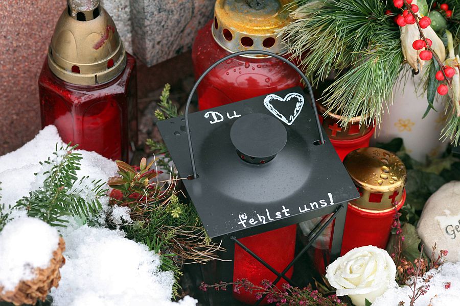 Grab mit Blumen, Kerzen und Laterne, leicht von Schnee bedeckt