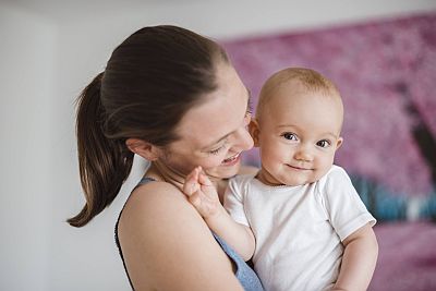 Mutter hält lachendes Baby auf dem Arm