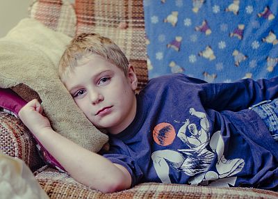 Junge liegt müde auf Sofa