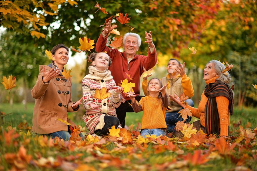 Großfamilie spielt mit Herbstblättern